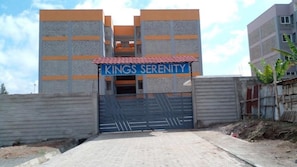 Uma entrada com portão para um edifício com uma placa indicando 'KINGS SERENITY'.