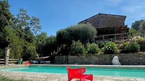 Una piscina con un muro de piedra y una silla roja al frente.