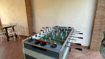 Ein Fußballtisch in einem Raum mit Fliesenboden, einer Ziegelwand und einer weißen Decke.