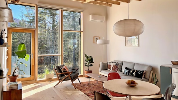 A modern living room with large windows, a wooden ceiling, a sofa, a dining table, and a potted plant. - Moritz - Modern Cabin - Stunning Hunter Mountain View (Hunter)