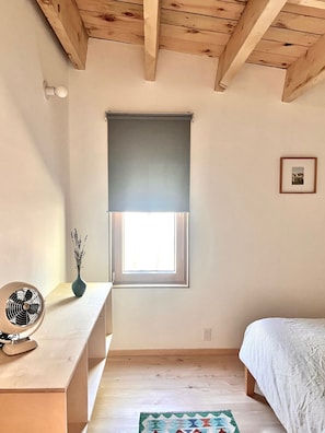 Une pièce avec une fenêtre, un ventilateur, un cadre et un lit.