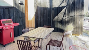 An outdoor patio with a wooden table and chairs, a red grill, and a yellow canopy. - Moritz - Modern Cabin - Stunning Hunter Mountain View (Hunter)
