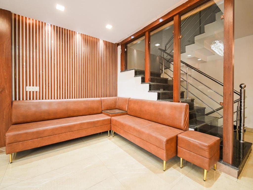 Uma sala de estar moderna com sofá seccional, escada de vidro e parede de destaque em madeira.