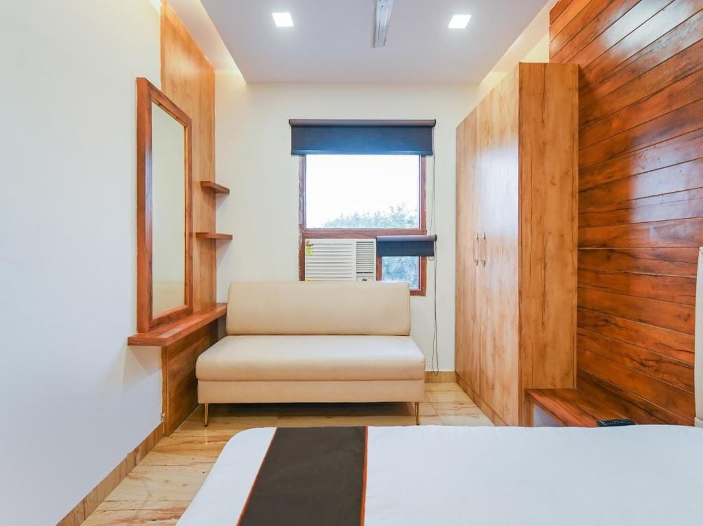Una habitación con sofá, ventana con persianas, radiador y paneles de madera en las paredes.