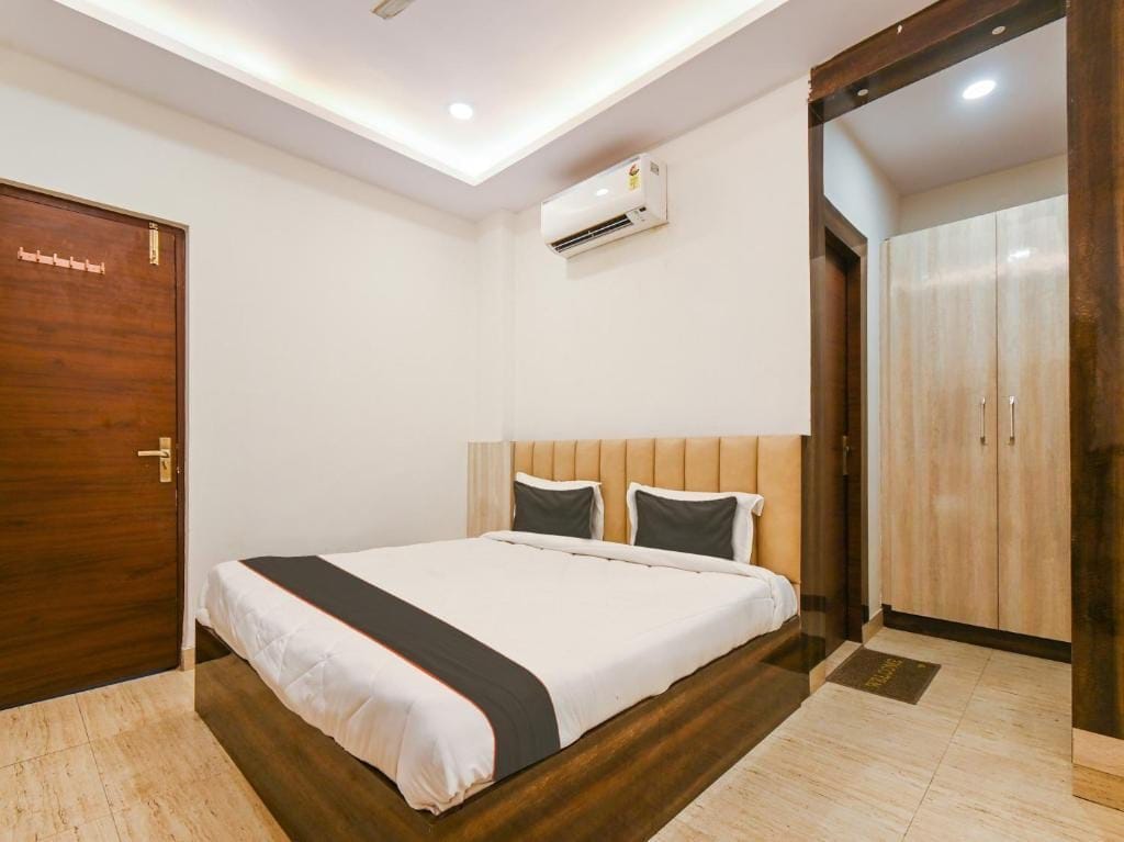 Una habitación de hotel con una cama, un equipo de aire acondicionado, un armario y una puerta.