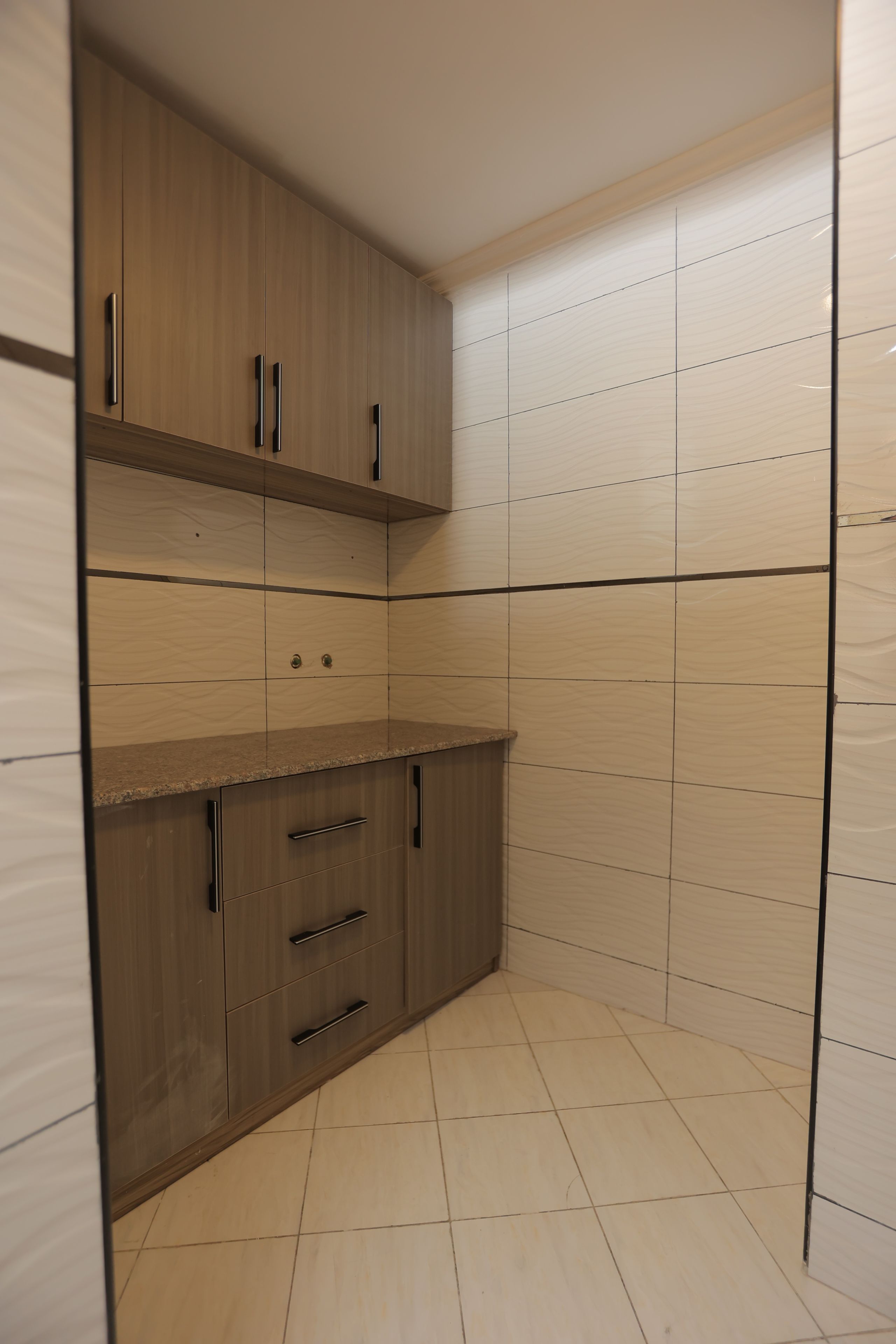 Una cocina con armarios de madera, una encimera y paredes con azulejos.