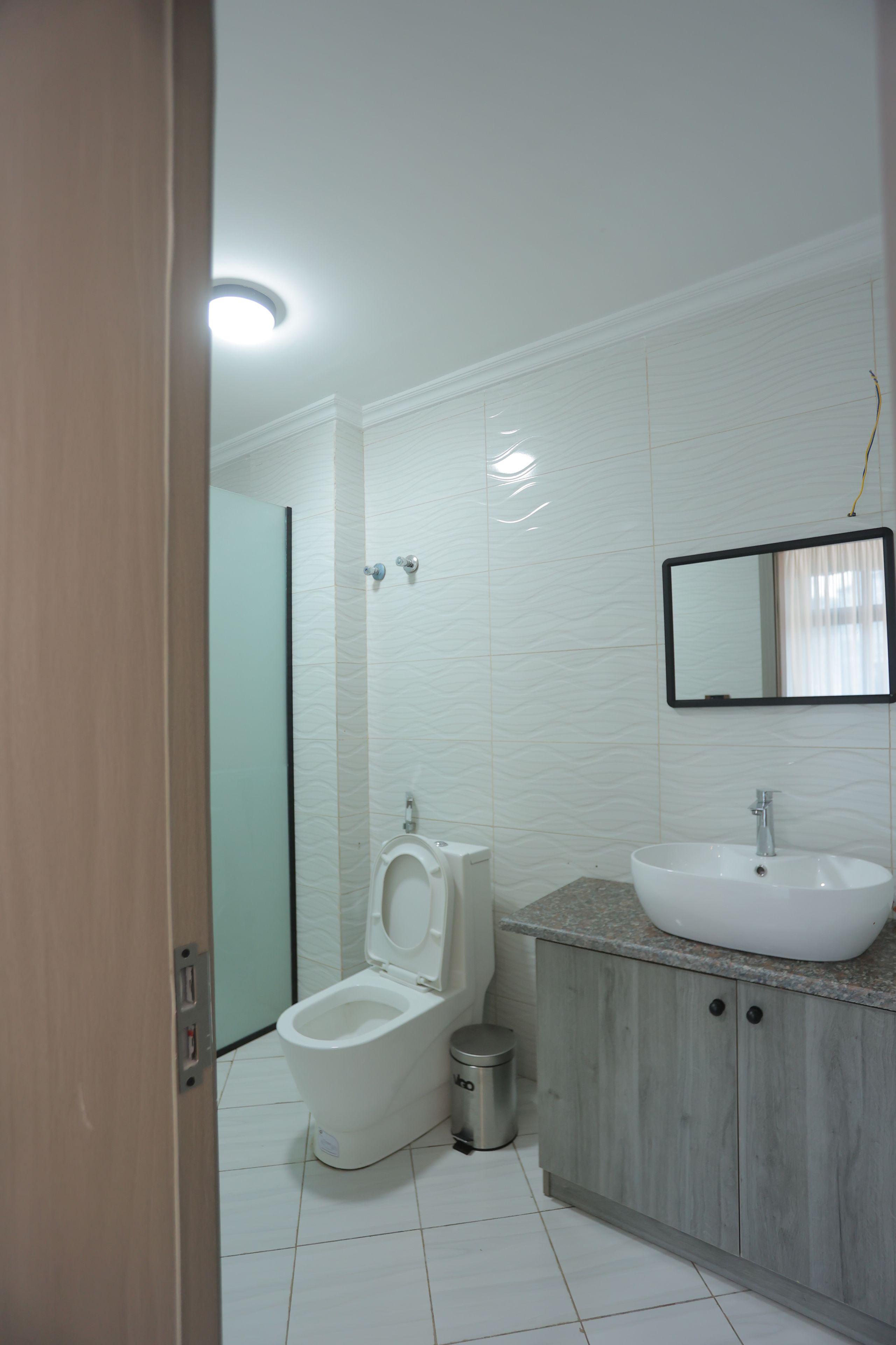 Un bagno moderno con un WC, un lavandino e uno specchio.