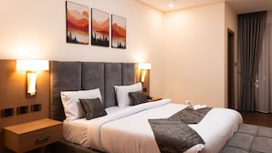Una habitación de hotel con una cama grande, dos mesitas de noche y una lámpara de pared.