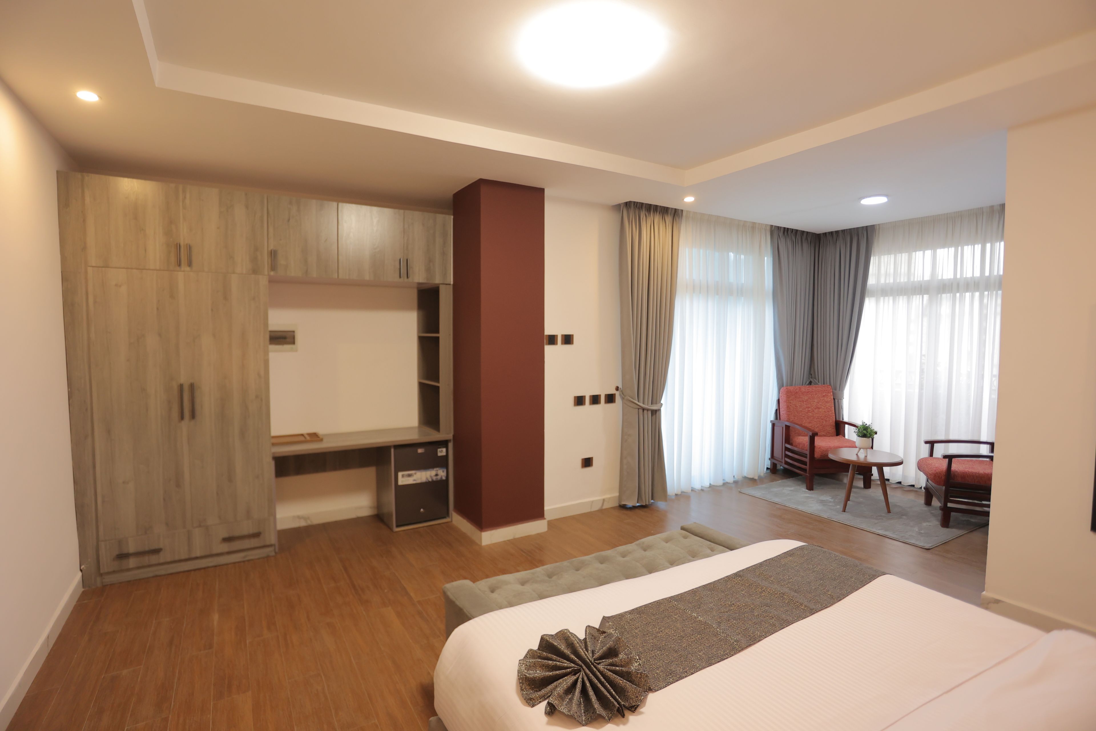 Ein Hotelzimmer mit Bett, Schreibtisch, Stuhl, Kleiderschrank und einem Fenster mit Vorhängen.