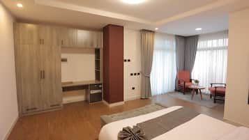Una camera d'albergo con un letto, una scrivania, una sedia, un armadio e una finestra con tende.