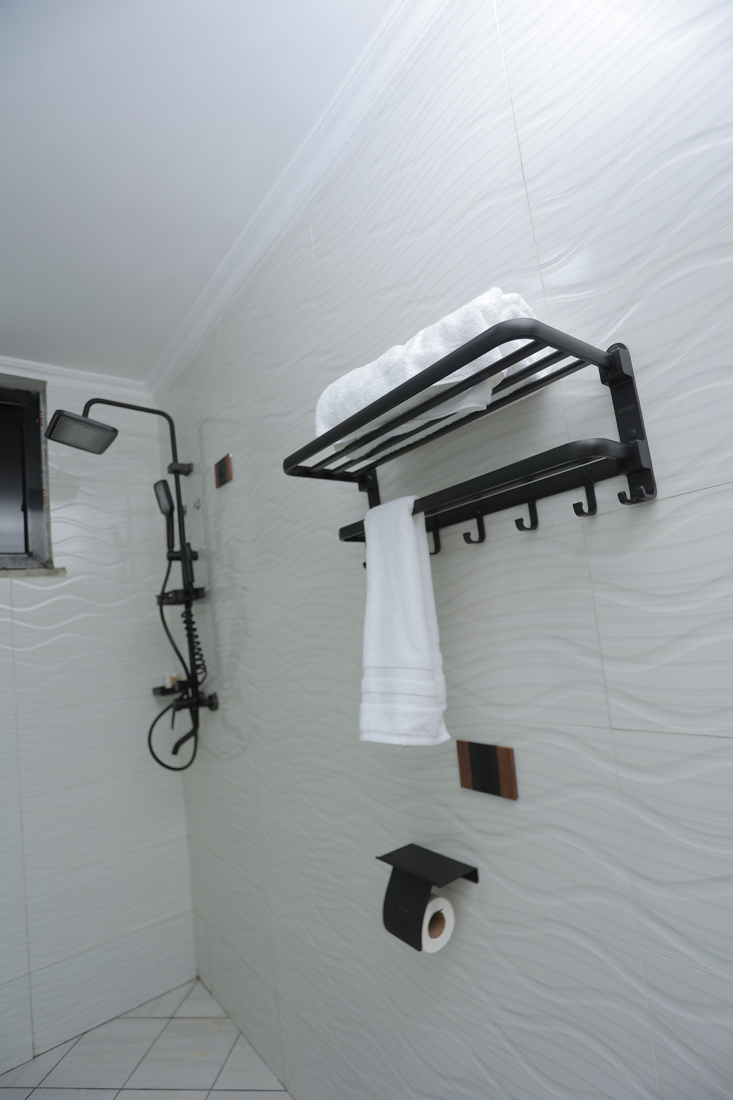A bathroom with a shower, towel rack, and toilet paper holder.