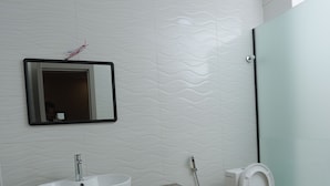 Un baño con lavabo blanco, espejo, inodoro y zona de ducha.