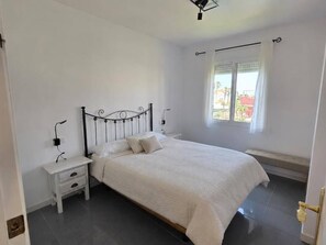 A bedroom with a bed, bedside tables, a window with curtains, and a door. - Amber Apartment by Staycare (Rota)