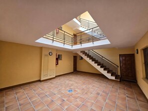A spacious interior with a tiled floor, a staircase, and a skylight. - Amber Apartment by Staycare (Rota)