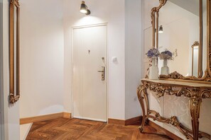 A hallway with a white door, a mirror, and a console table with a vase. - Jana's Garden House With Hot Tub (Kamnik)