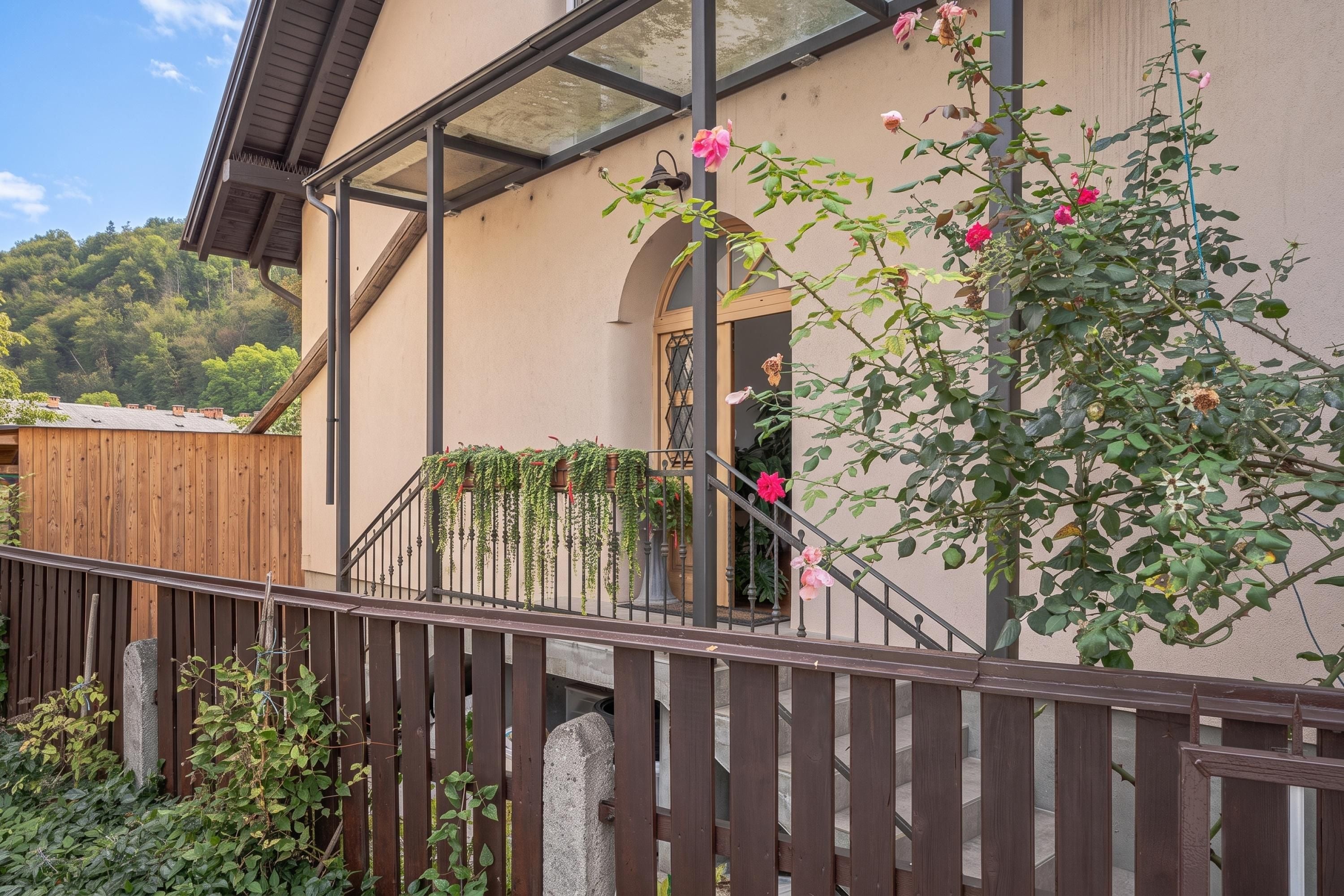 A building with a wooden fence, a staircase, and a garden with roses.