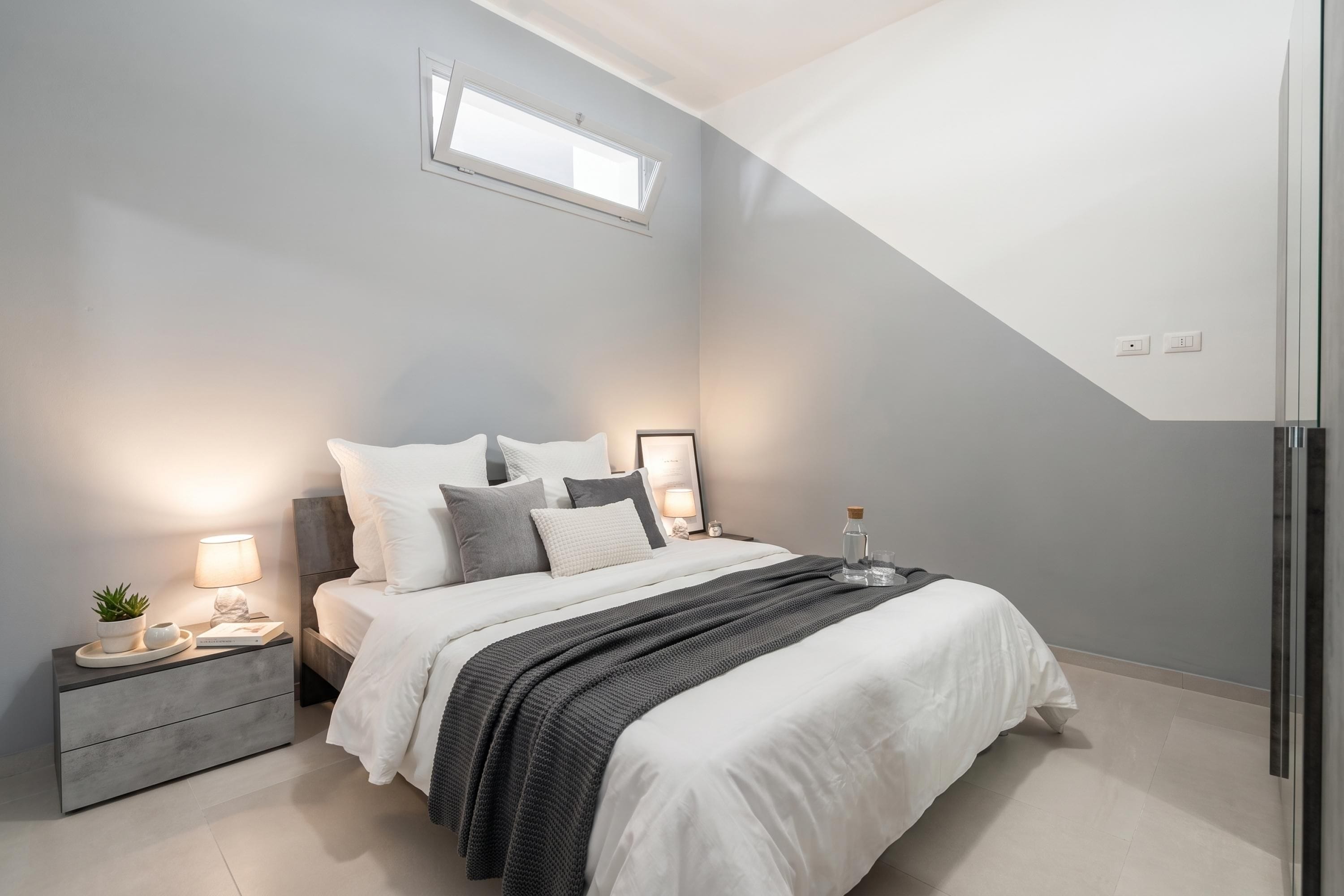 A modern bedroom with a bed, bedside tables, a nightstand, a window, and a built-in wardrobe.