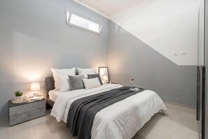 Ein modernes Schlafzimmer mit Bett, Nachttischen, Fenster und einem integrierten Kleiderschrank.