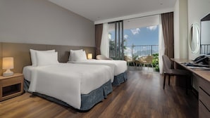 A hotel room with two beds, a desk, a chair, and a balcony with a view. - Cat Ba Sea & Sand Resort (Cat Hai)
