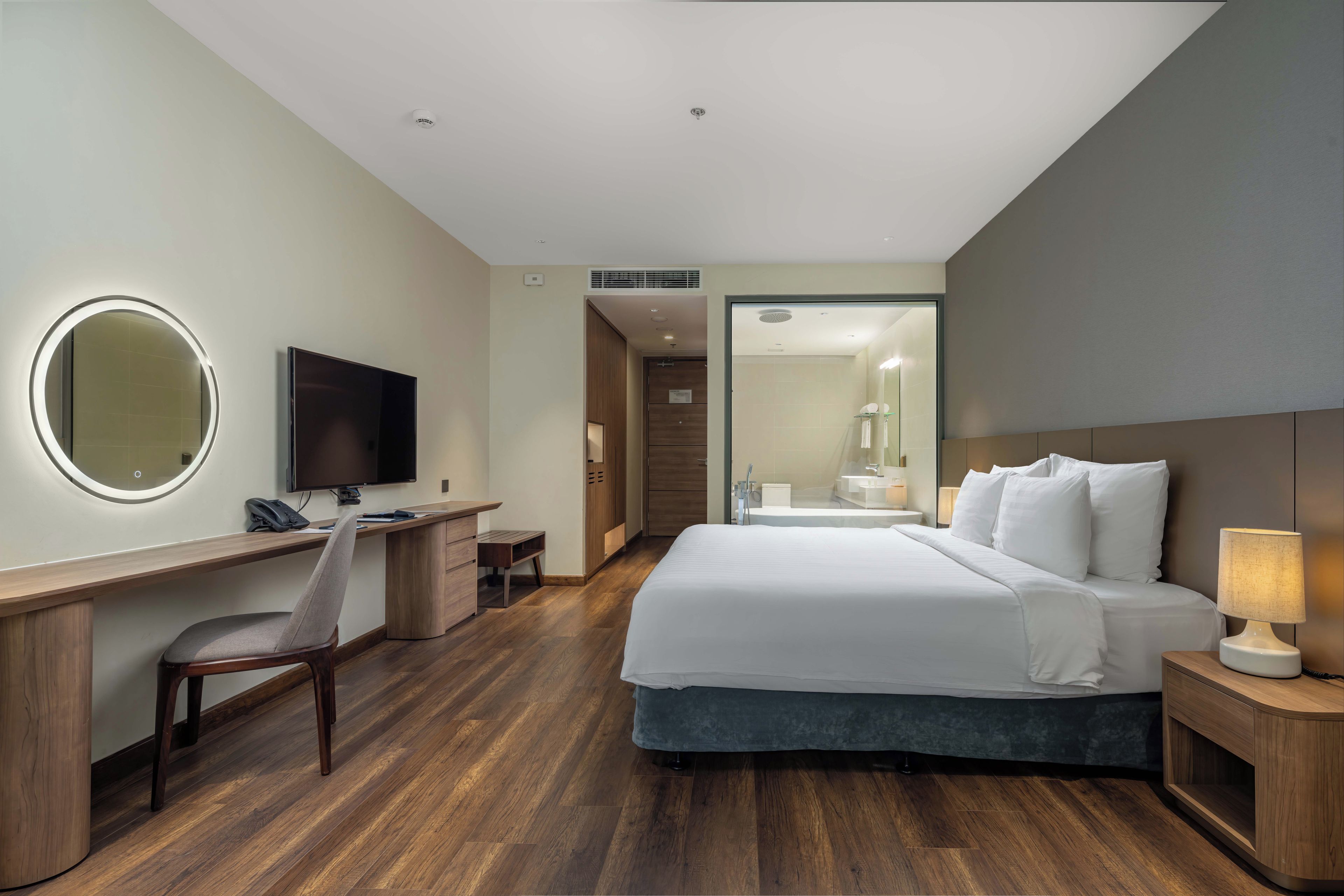 A hotel room with a bed, desk, chair, TV, and a bathroom visible through an open door.
