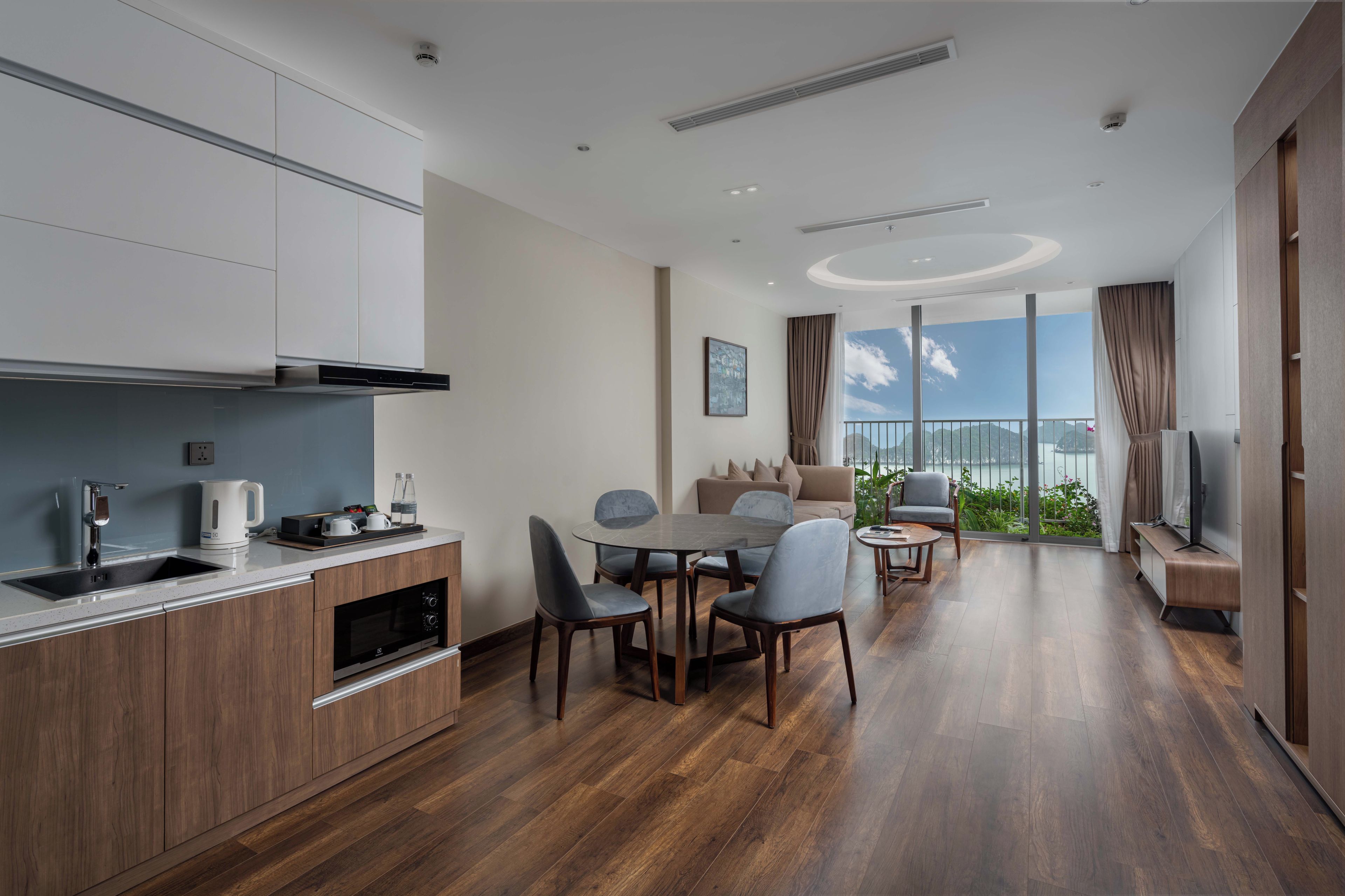 A modern kitchen with a built-in oven and a dining area with a round table and chairs.