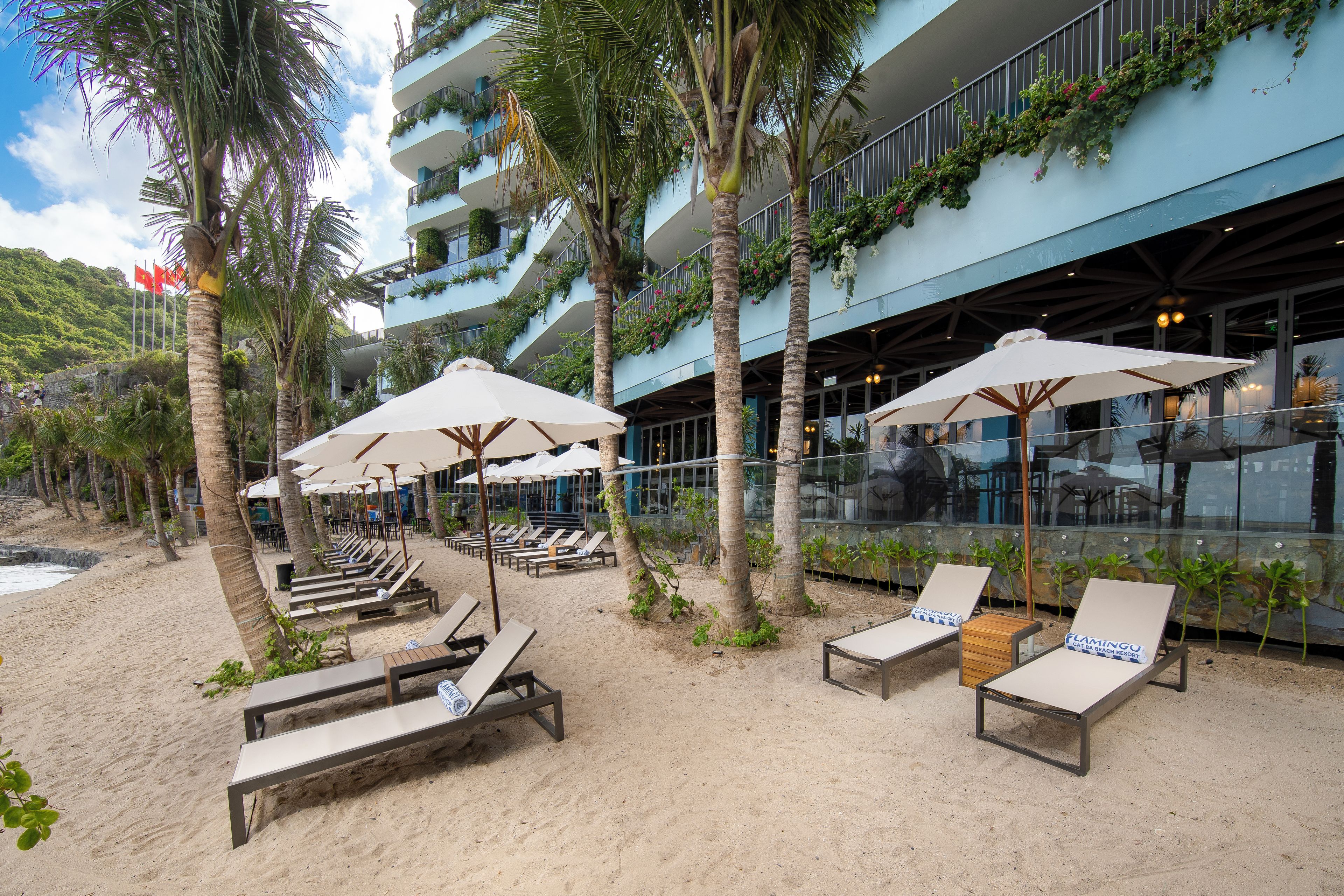 A beachfront hotel with sun loungers, umbrellas, and a view of the sea.