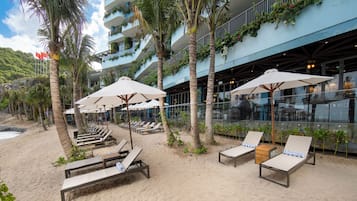 A beachfront hotel with sun loungers, umbrellas, and a view of the sea.
