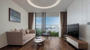 A modern living room with a sofa, a chair, a coffee table, a TV, and a balcony with a view.
