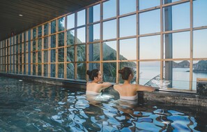 A swimming pool with a view of a mountainous landscape through large windows.