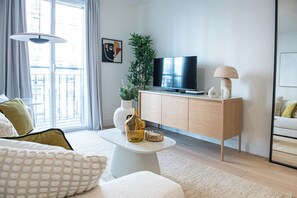 Un salon moderne avec un téléviseur à écran plat, un meuble en bois, une table basse blanche et un canapé.