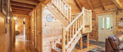 Un intérieur en bois avec un escalier menant à une mezzanine, une porte décorée d’un motif en forme de flocon de neige et un canapé en cuir.