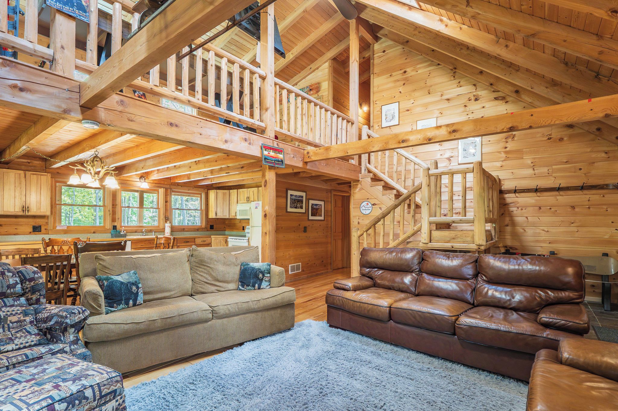 Un intérieur de chalet en bois spacieux, doté d’un plafond haut, d’un escalier, d’un coin repas et d’un salon aménagé avec des canapés et une table basse.