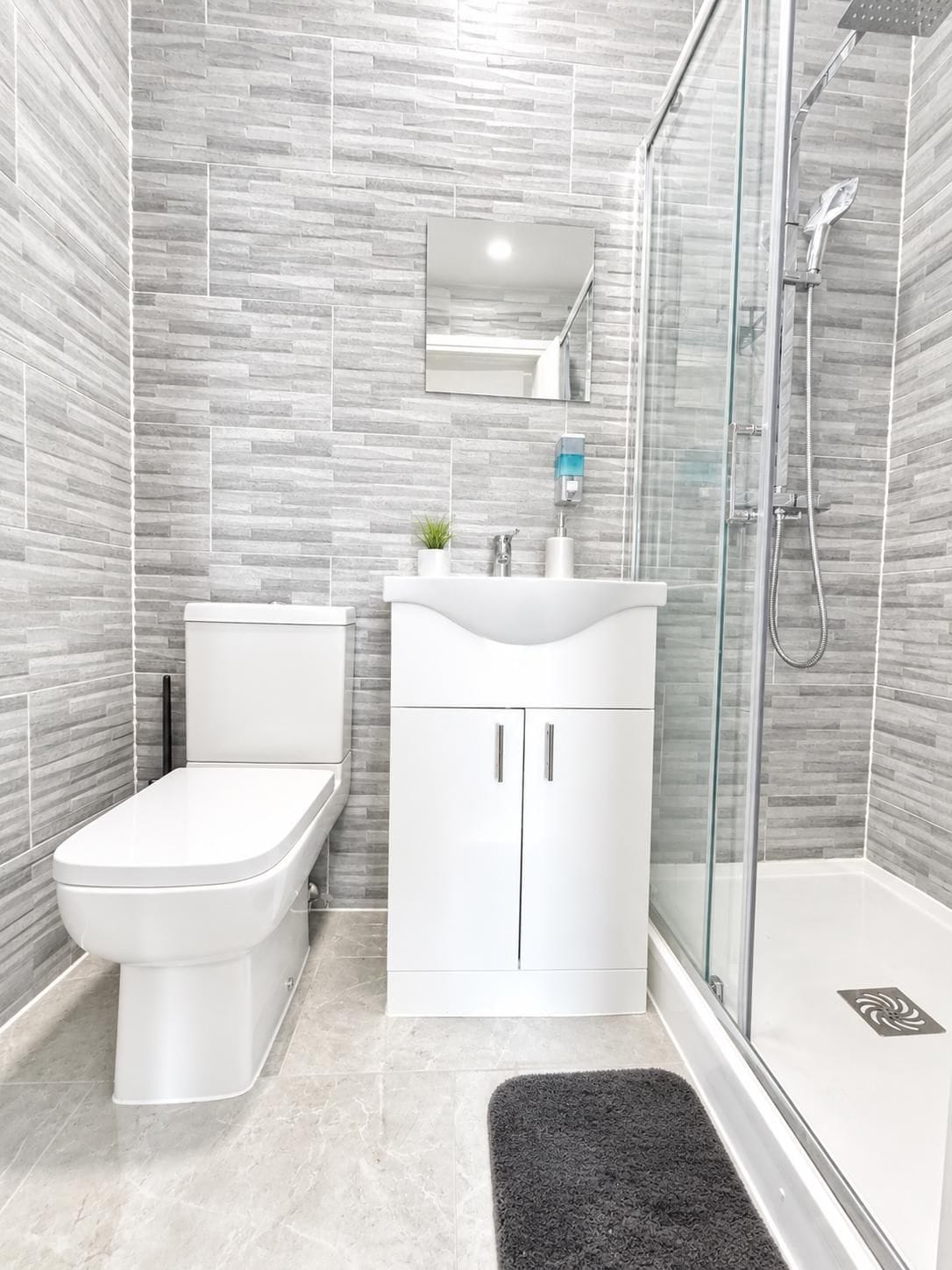 A modern bathroom with a toilet, sink, and shower.
