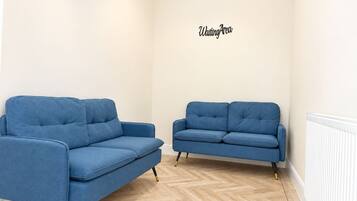 Una habitación con dos sofás azules y un cartel en la pared que dice 'Waiting Area'.