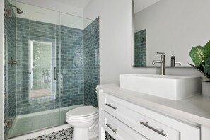Un bagno moderno con cabina doccia in vetro, lavabo bianco e uno specchio grande.