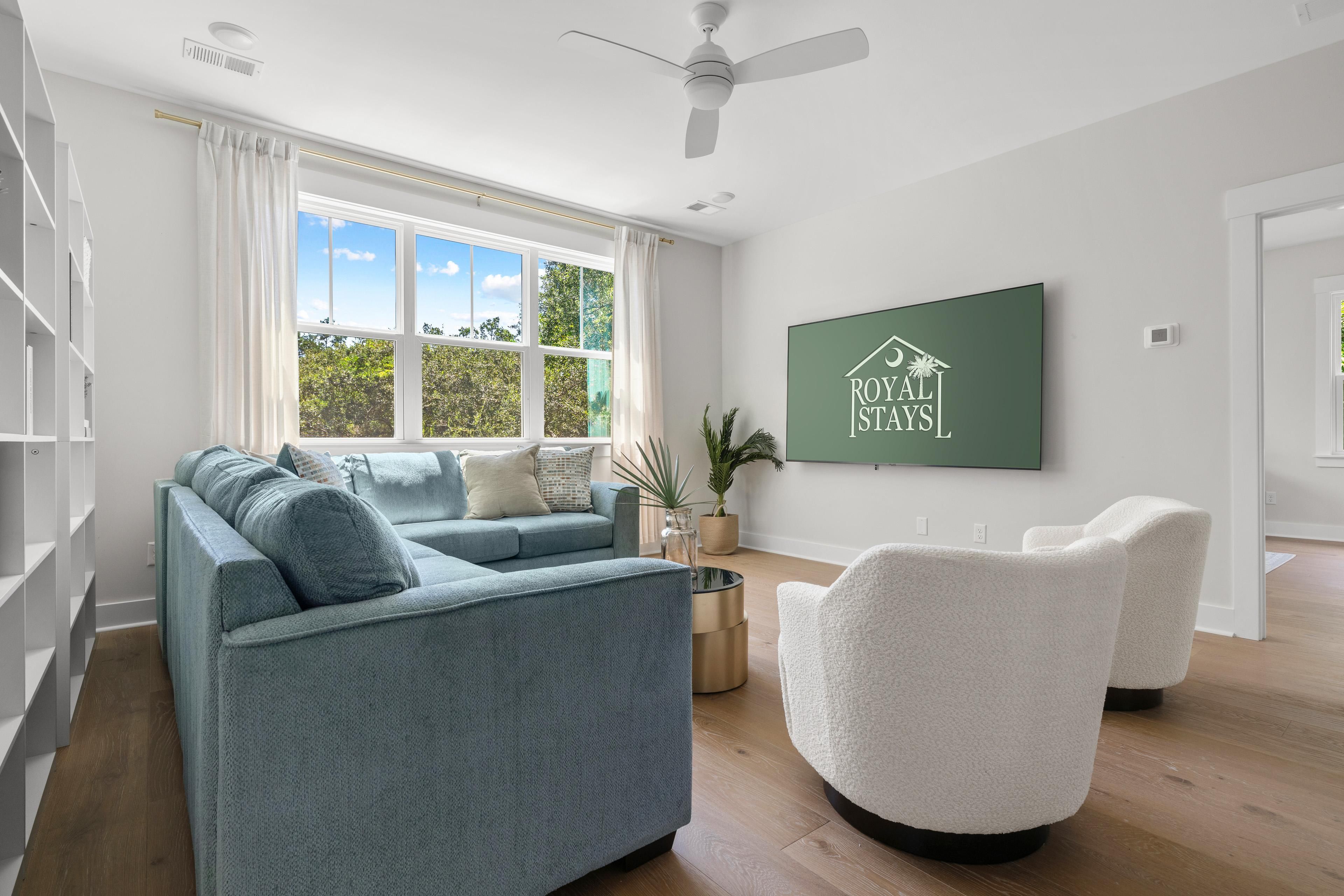 A modern living room with a sofa, armchairs, a coffee table, and a large window with a view of trees.