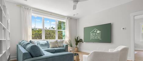 A modern living room with a sofa, armchairs, a coffee table, and a large window with a view of trees.