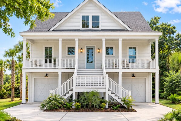 Una casa a due piani con un portico, un garage e un giardino curato.