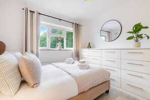 A bedroom with a bed, a dresser, a mirror, and a window with curtains. - Modern 1-bed-Parking-Garden-Nr Warner Bros (Watford)