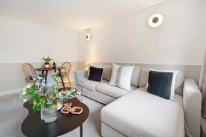 Uma sala de estar moderna com sofá, mesa de centro e área de jantar com cadeiras e mesa.
