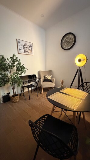 A living room with a round table, two chairs, a floor lamp, a wall clock, a framed artwork, and a potted plant. - VARANDAS DO PORTO COLIVING (Porto)