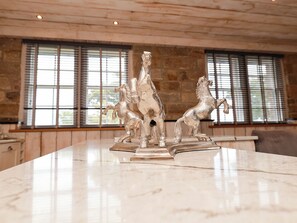 A marble countertop with a silver horse sculpture in a room with stone walls and large windows. - The Stables at The Castle (Whitby)