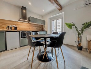 Een moderne keuken met een eethoek, met een houten plafond, een groot raam en een potplant.