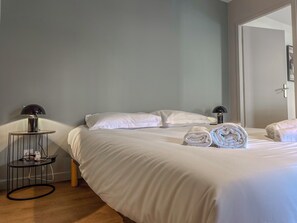 Een hotelkamer met een bed, twee bedlampen, een ronde tafel met een lamp en handdoeken op het bed.