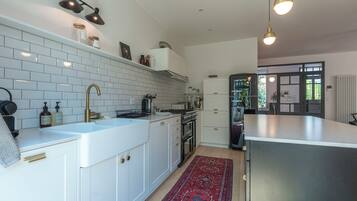 Une cuisine moderne avec des meubles blancs, un îlot central et un tapis à motifs rouges.