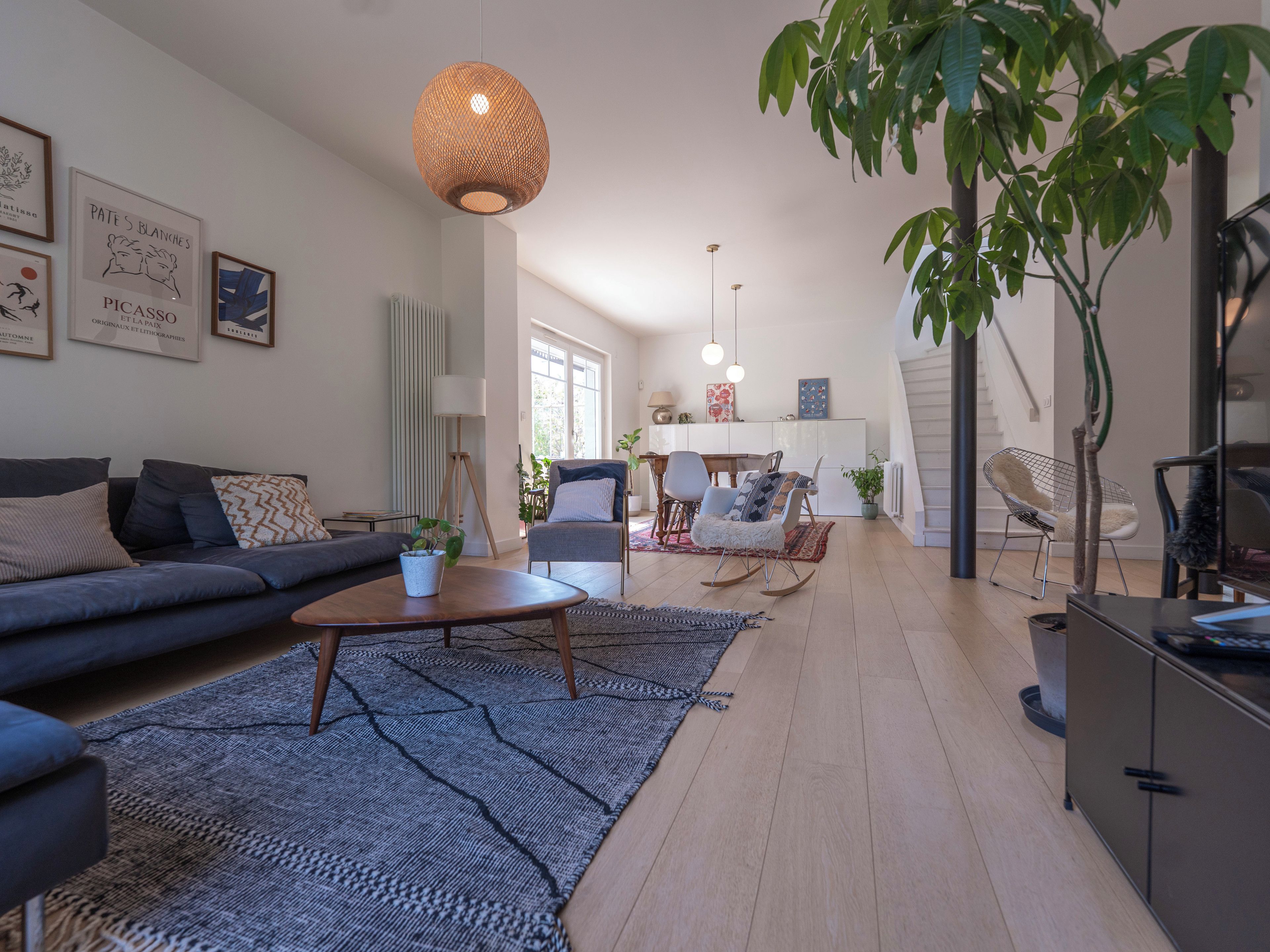 Un salon moderne comprenant un canapé, une table basse et un coin repas avec des chaises.