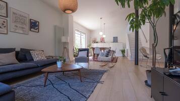 Un salon moderne comprenant un canapé, une table basse et un coin repas avec des chaises.