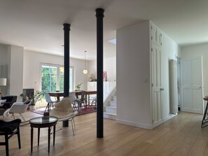 Een ruime woonkamer met een eettafel, stoelen en een trap naar een verdieping.
