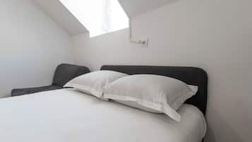 A bedroom with a bed, a window, and a wall-mounted light fixture.
