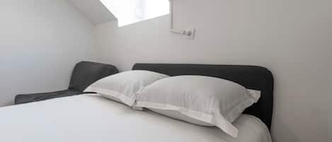 A bedroom with a bed, a window, and a wall-mounted light fixture.